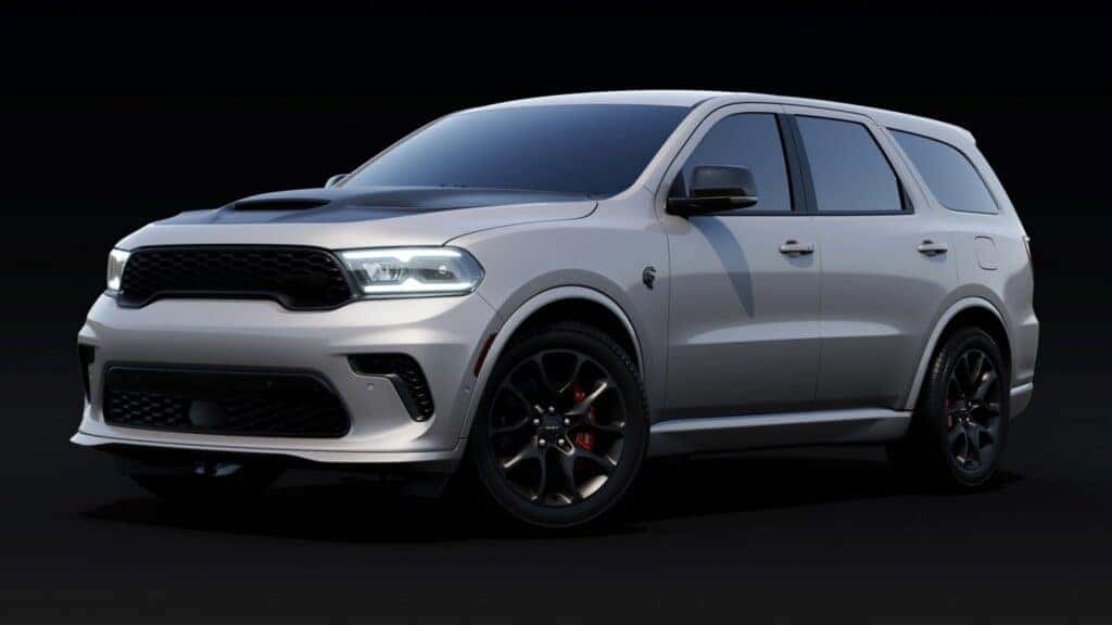 Silver SUV with sleek design and black rims, shown in a dark studio setting.