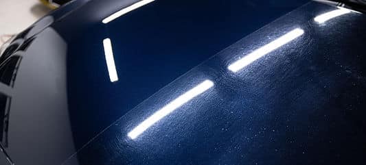 Blue car hood showing before and after paint correction