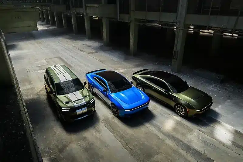Three cars — a green SUV, a blue sports car, and a green sedan — parked in an empty warehouse.