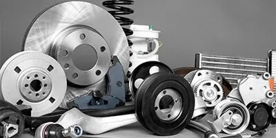 Assorted car parts including brake discs, suspension springs, and wheels on a gray background.